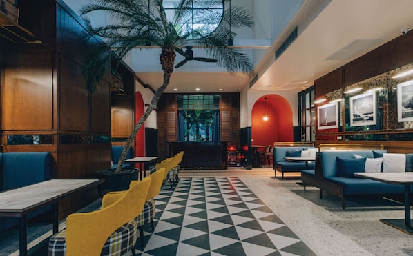 A modern interior with a checkered floor, wooden furniture, and a central plant.