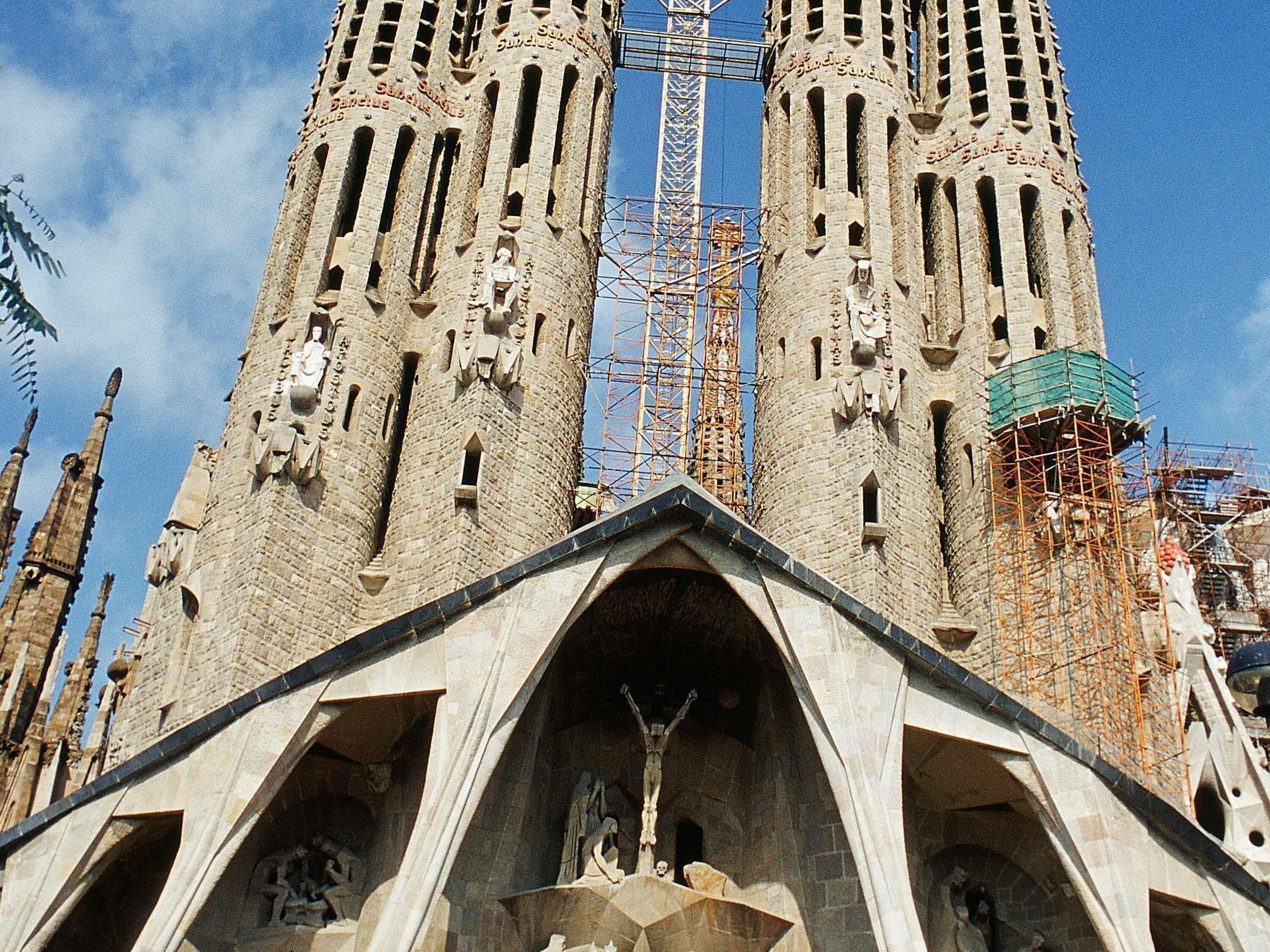 A historic building with two tall towers, a central entrance, and a statue at the base.