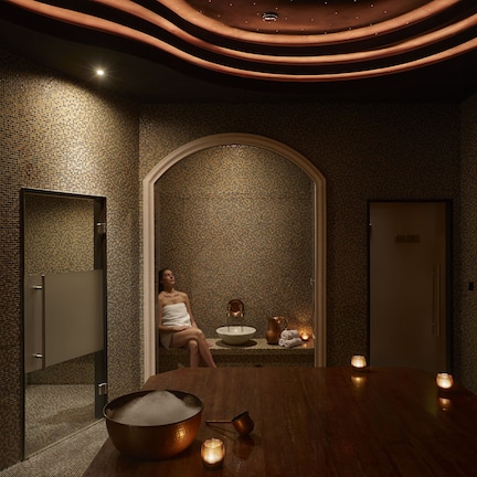 A spa room with a wooden table, a large bowl, and candles.