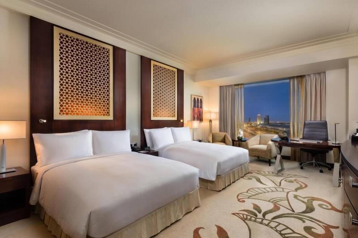 Une chambre d’hôtel avec deux lits, un bureau, une chaise et une vue sur la ville.