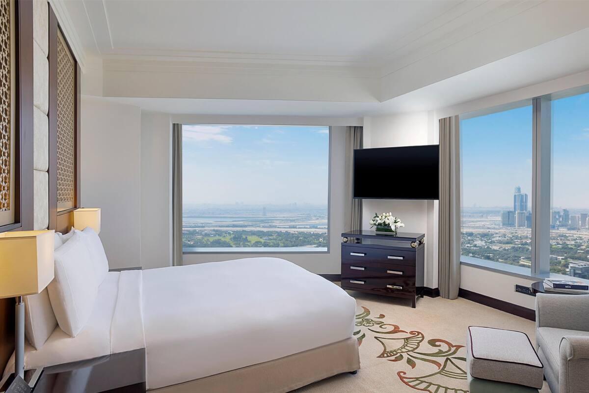 Une chambre d’hôtel avec un grand lit, une télévision, un bureau et une vue sur la ville.