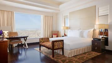 Habitación de hotel con una cama grande, un escritorio con silla, una mesita de noche y vistas a la ciudad.
