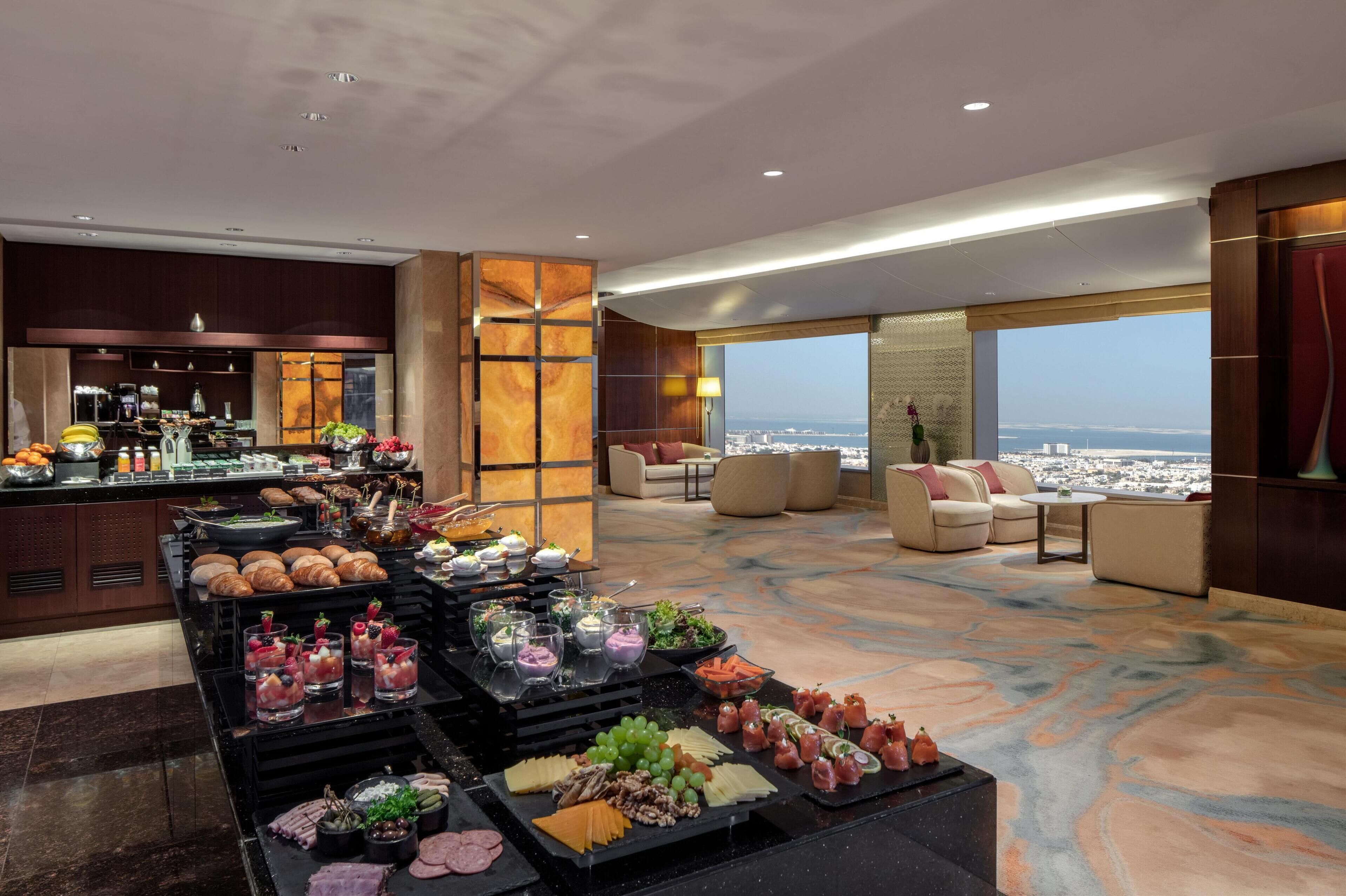 Un hall d’hôtel avec un buffet, un espace salon et une vue sur la ville.
