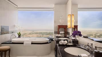 Um banheiro moderno com uma banheira grande, duas pias e vista para uma paisagem desértica.