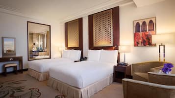 A hotel room with two beds, a desk, a chair, and a decorative mirror.