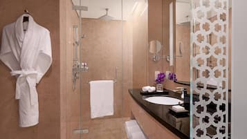 Une salle de bain moderne avec une douche à l’italienne en verre, une serviette blanche accrochée au mur et un meuble-lavabo avec un miroir et un évier.