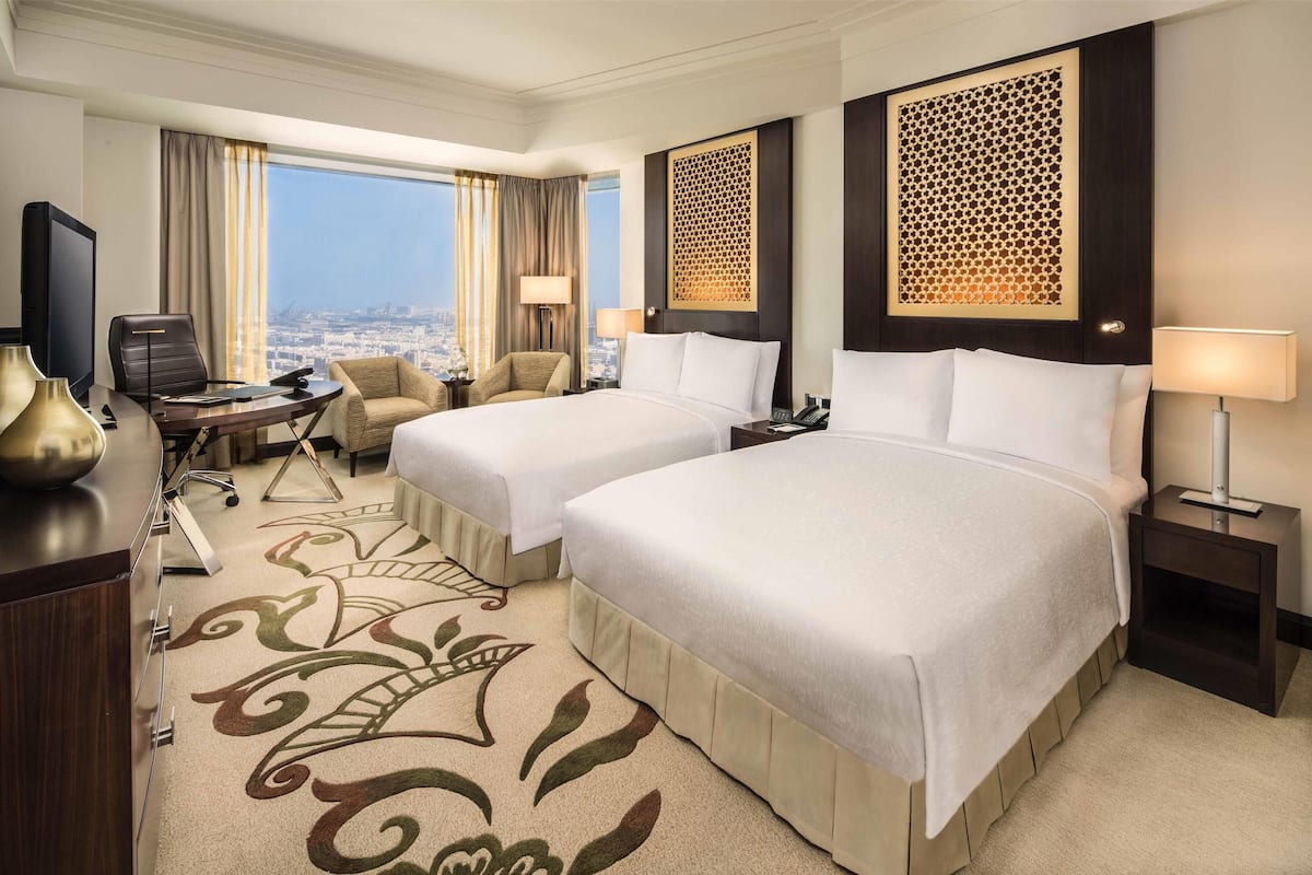 Une chambre d’hôtel avec deux lits, un bureau, une télévision et une vue sur la ville.