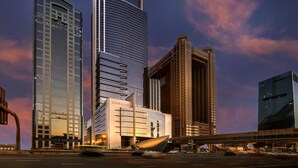 A modern skyscraper with "CONRAD" signage, surrounded by other high-rise buildings, under a twilight sky. - Conrad Dubai (Dubai)