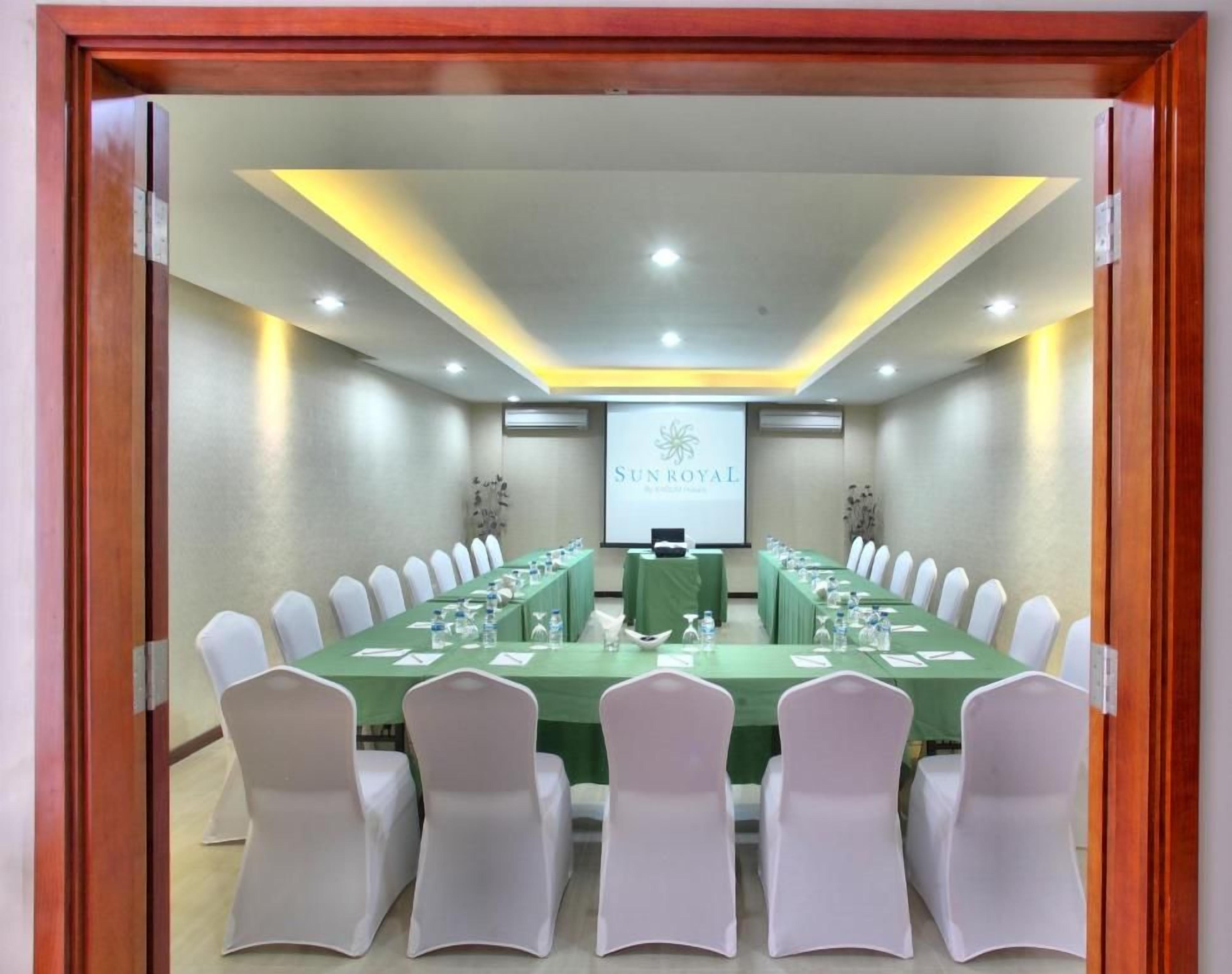 Une salle de conférence équipée d’une longue table, de chaises et d’un écran de présentation.