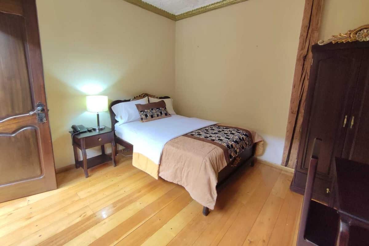Un dormitorio con cama, mesita de noche, lámpara y armario.