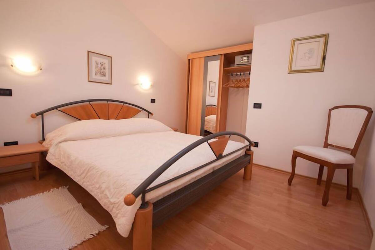 A bedroom with a bed, bedside tables, a chair, and a wardrobe.