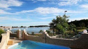 A swimming pool with a clear view of the surrounding landscape and a body of water in the distance. - Villa Vizula (Medulin)