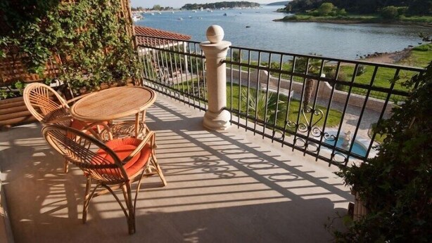 A balcony with a view of a river, a table with chairs, and a railing. - Villa Vizula (Medulin)