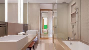 A modern bathroom with a large bathtub, a separate shower area, and a vanity with a bench.