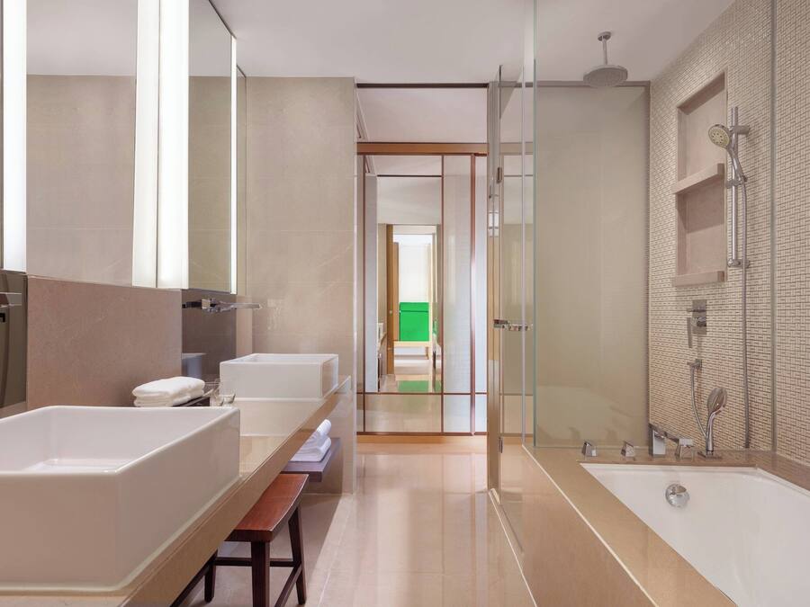 A modern bathroom with a large bathtub, a separate shower area, and a vanity with a bench.