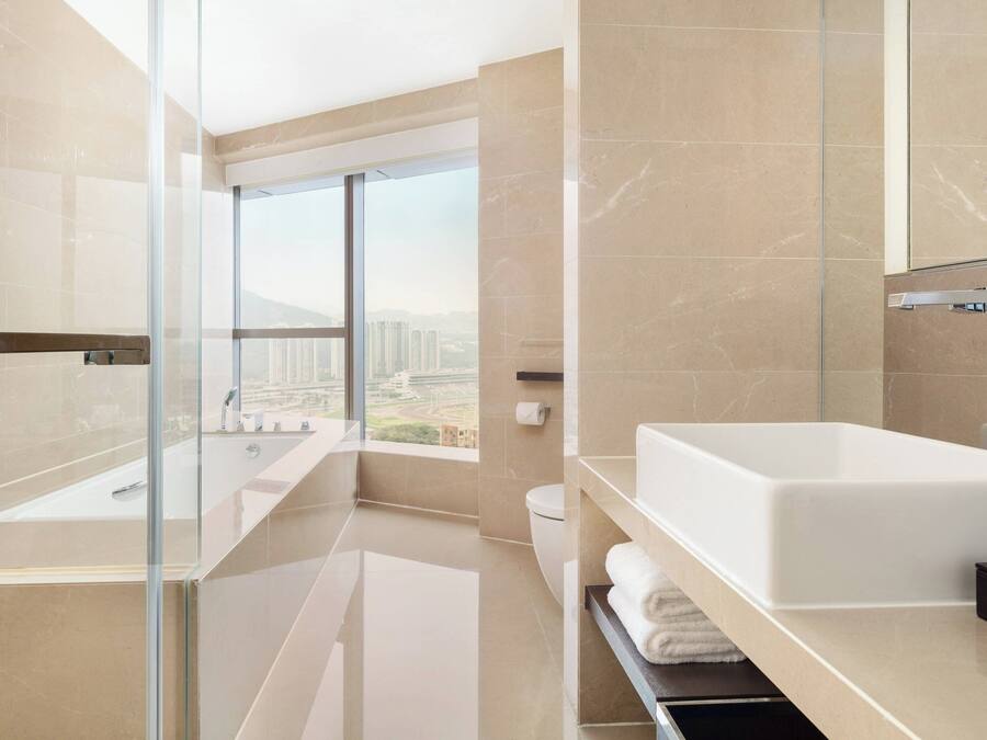 A modern bathroom with a large bathtub, a glass shower enclosure, and a view of the city.