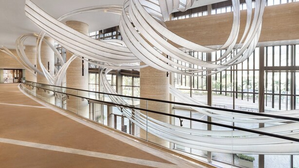 A spacious atrium with a modern, curvilinear ceiling design and large windows allowing natural light to fill the space.