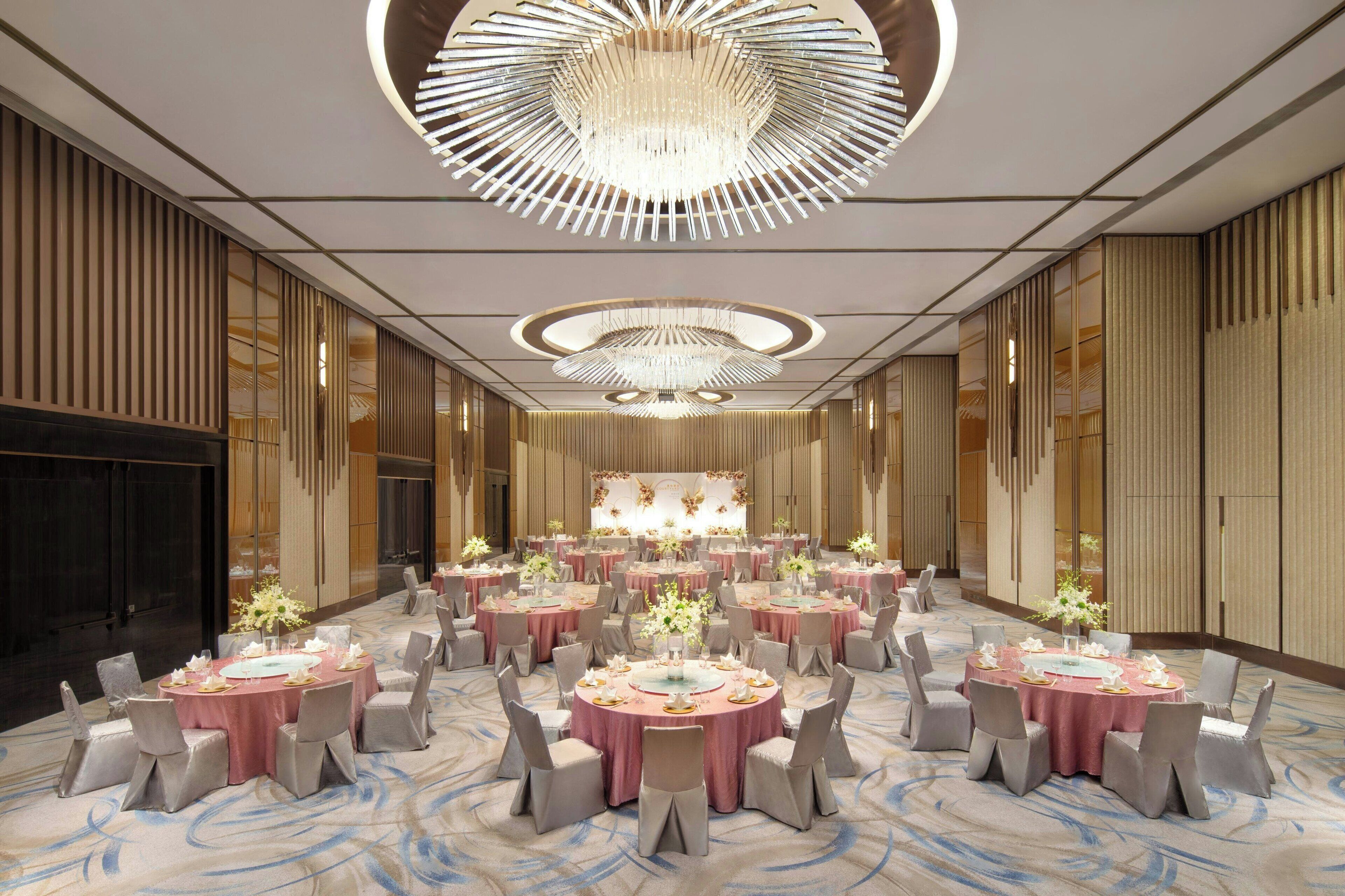 A spacious banquet hall with multiple round tables, each set with chairs and centerpieces.