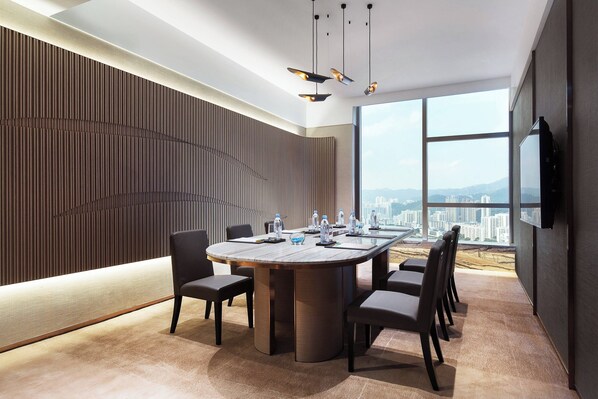 A modern conference room with a large round table, chairs, a city view, and a wall-mounted TV. - Courtyard by Marriott Hong Kong Sha Tin (Sha Tin)
