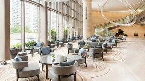 A spacious lobby with a curved staircase, large windows, and a modern design.