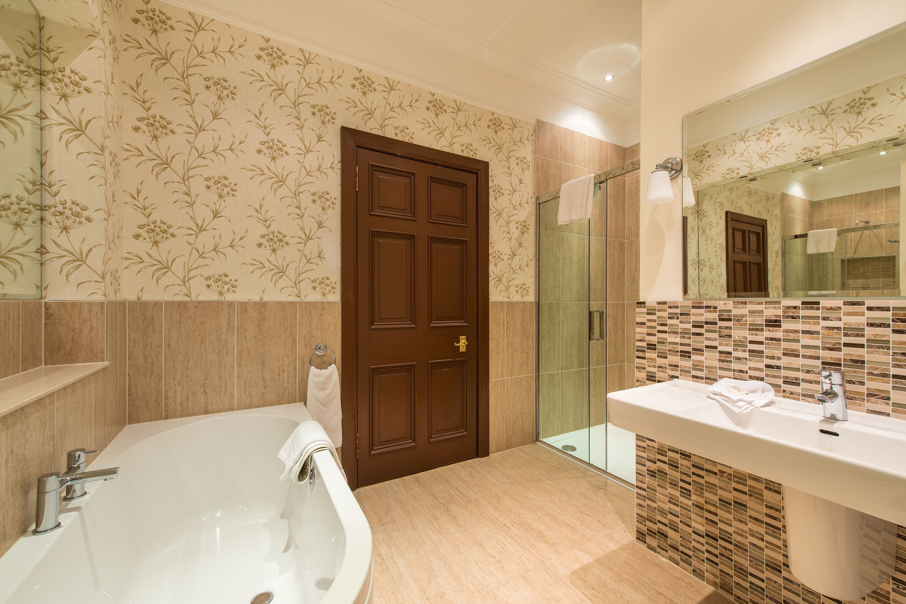 Un baño con una bañera grande, ducha y lavamanos con espejo.
