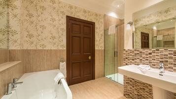 A bathroom with a large bathtub, a shower, and a sink with a mirror above it.