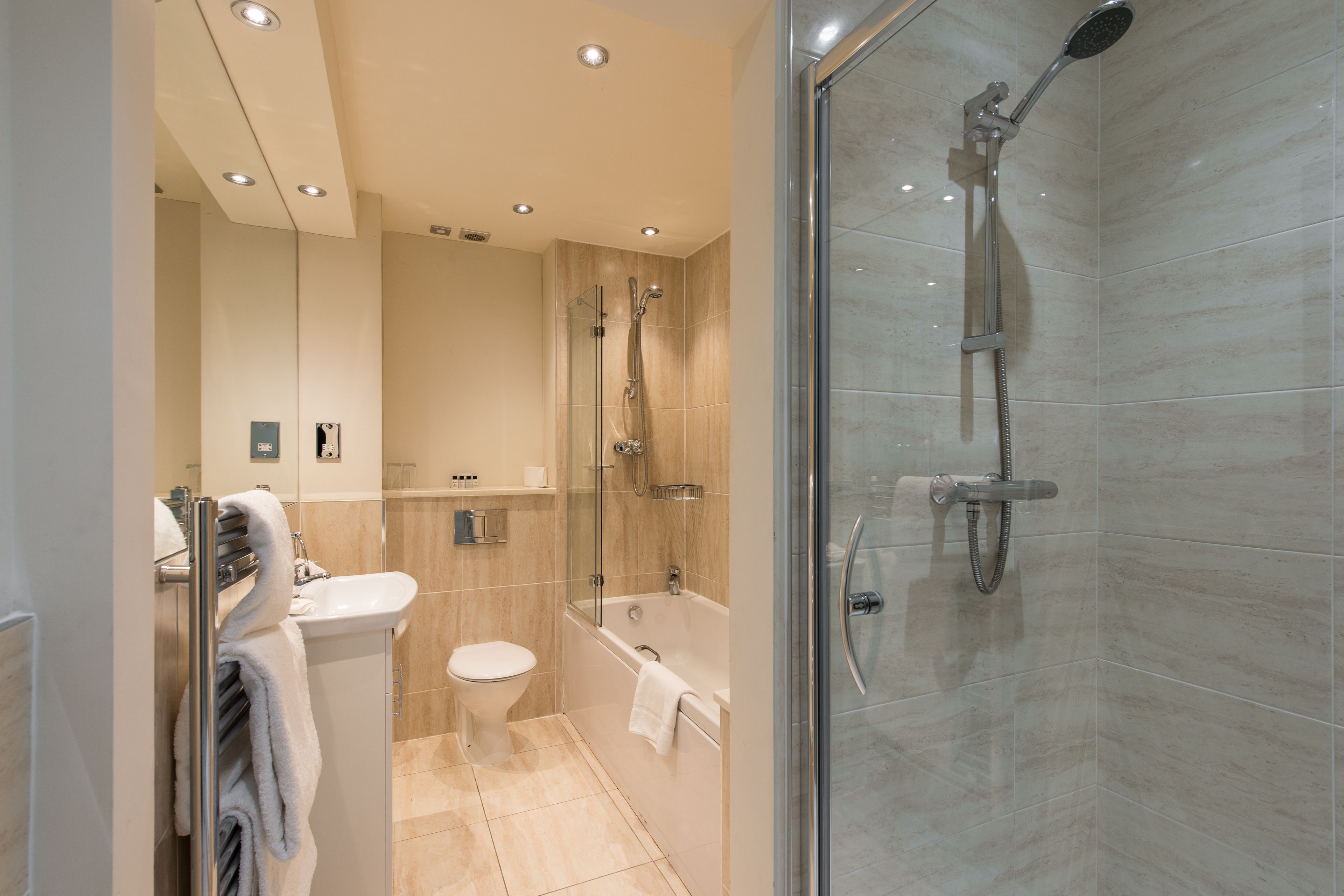 A modern bathroom with a glass-enclosed shower, a toilet, and a bathtub.