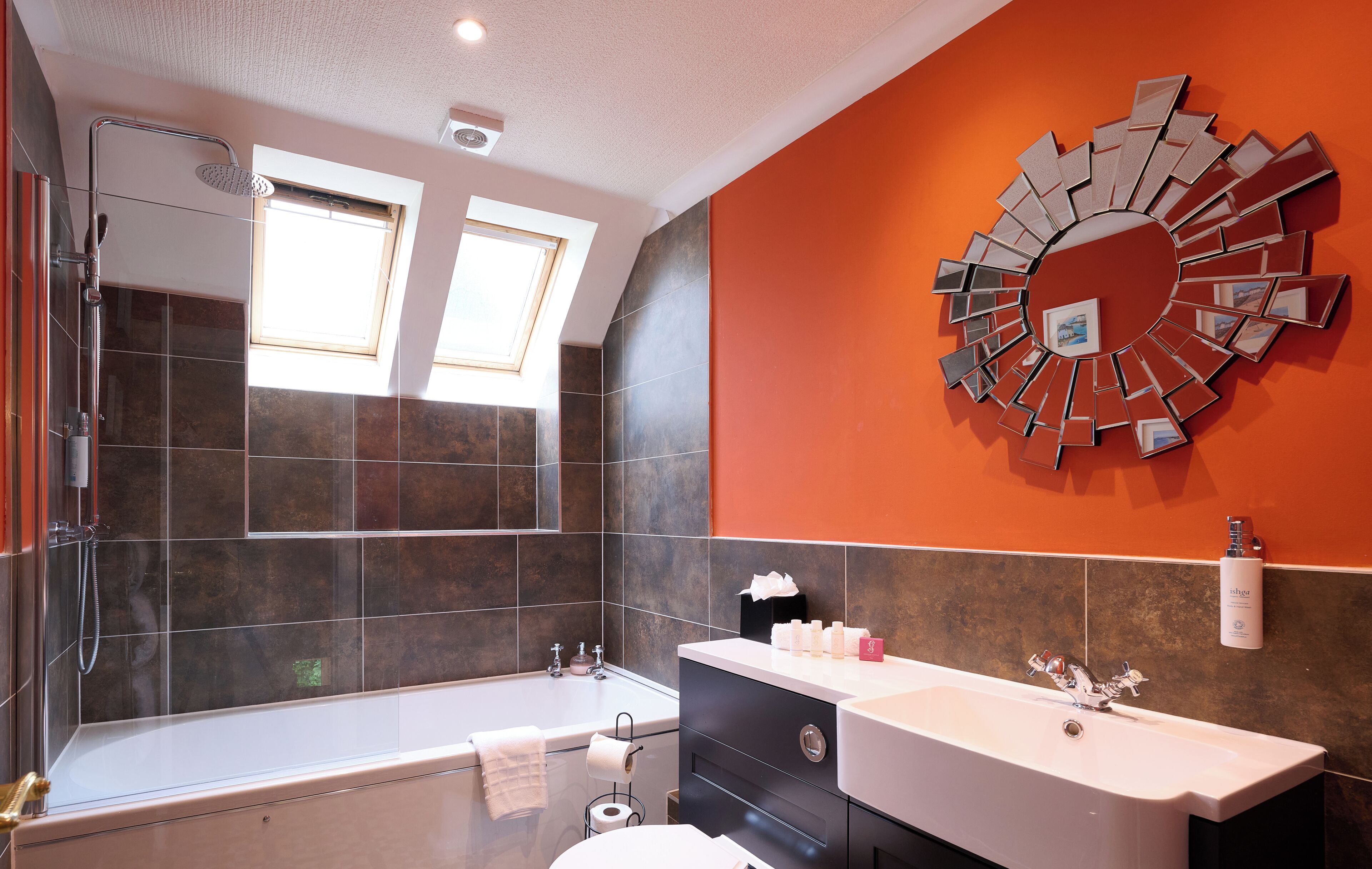 Un baño moderno con un espejo grande, una bañera y un tocador con lavamanos.