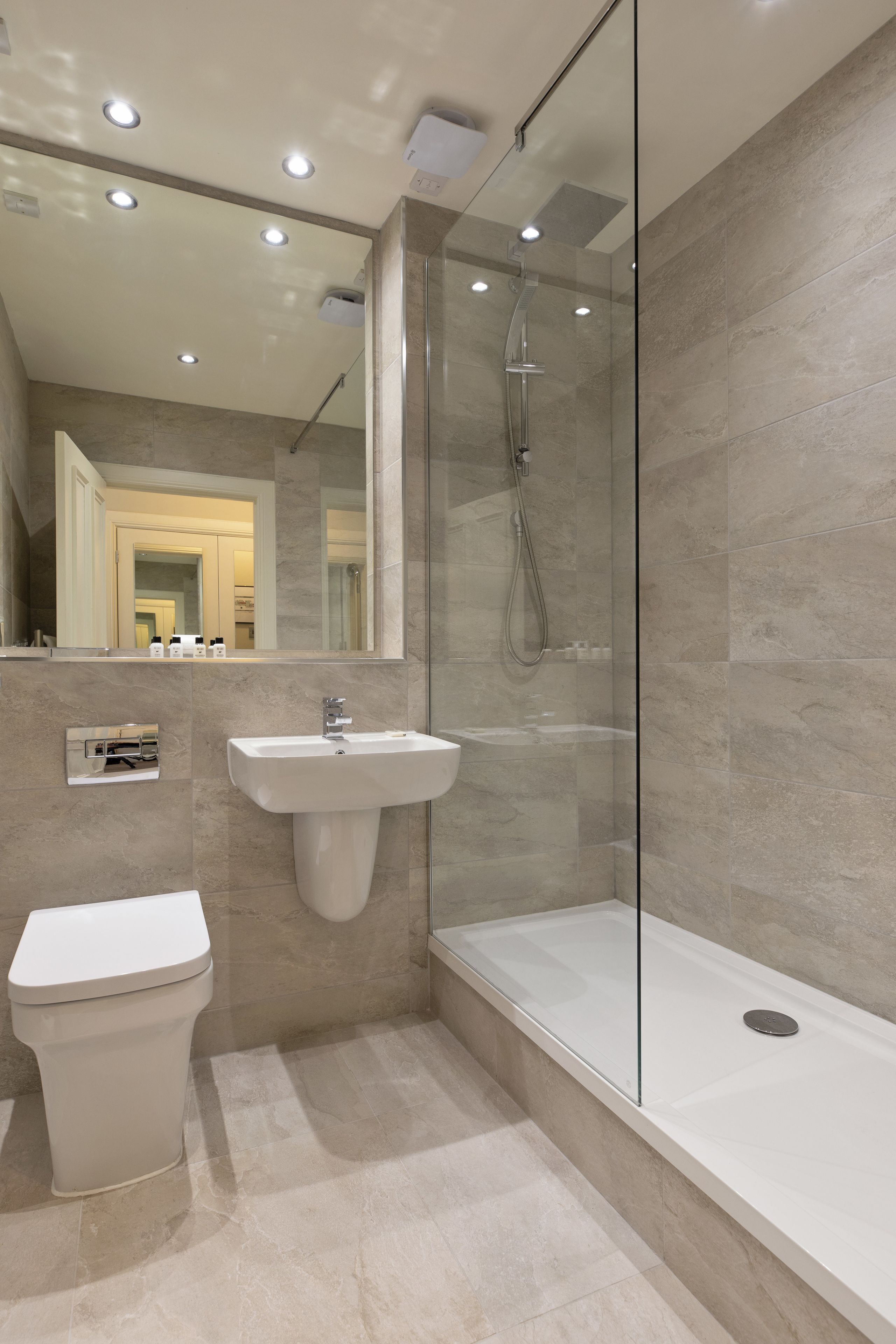 A modern bathroom with a glass-enclosed shower, a white sink, and a toilet.