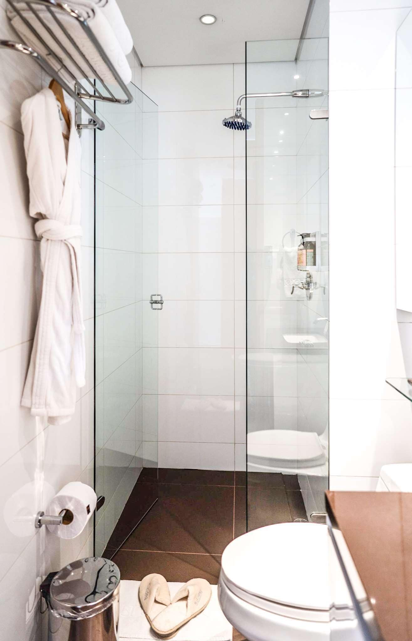 Ein modernes Badezimmer mit einer gläsernen Dusche, einer weißen Badewanne und einer Toilette.
