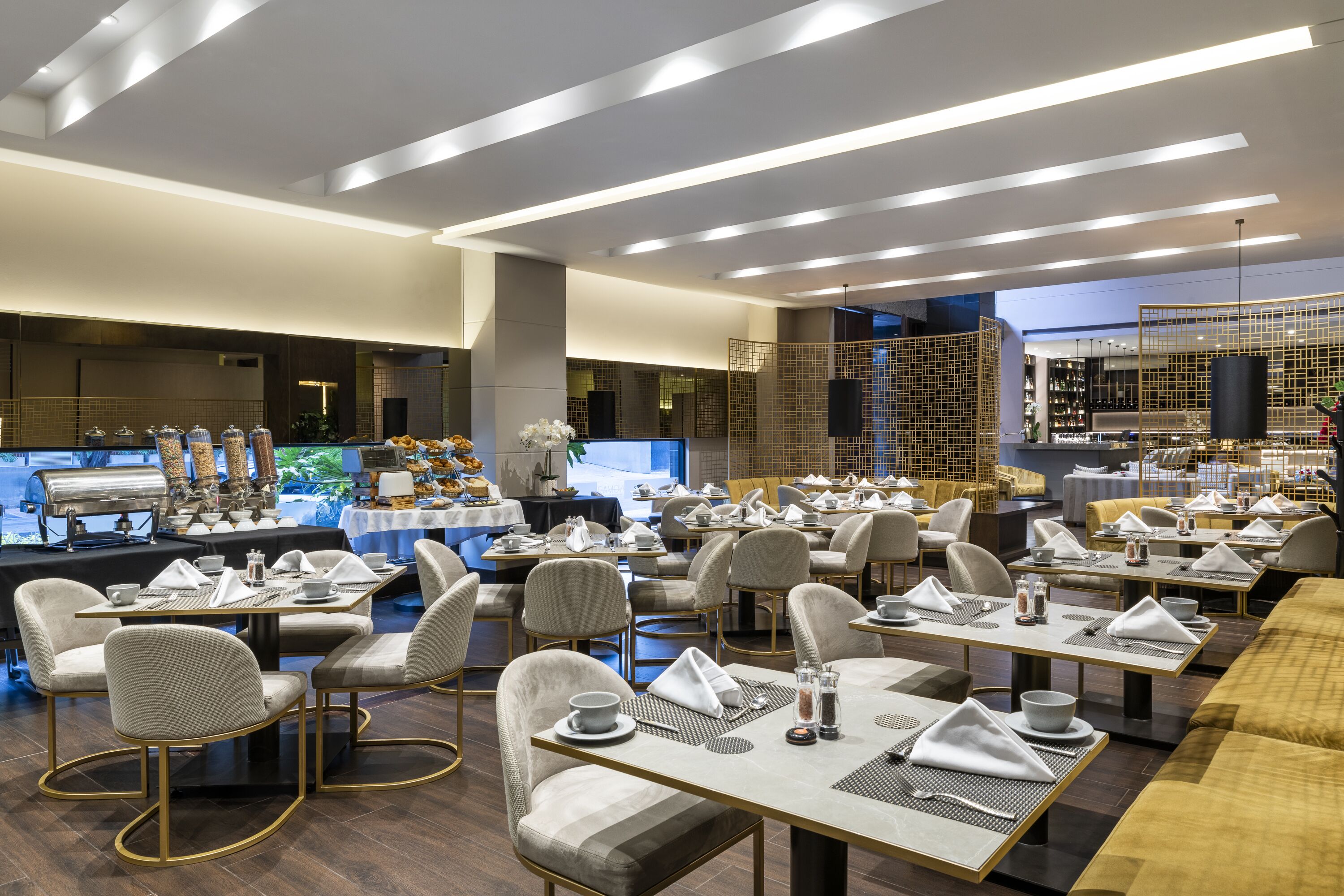 A modern restaurant with multiple dining tables and chairs, a buffet area, and a kitchen in the background.