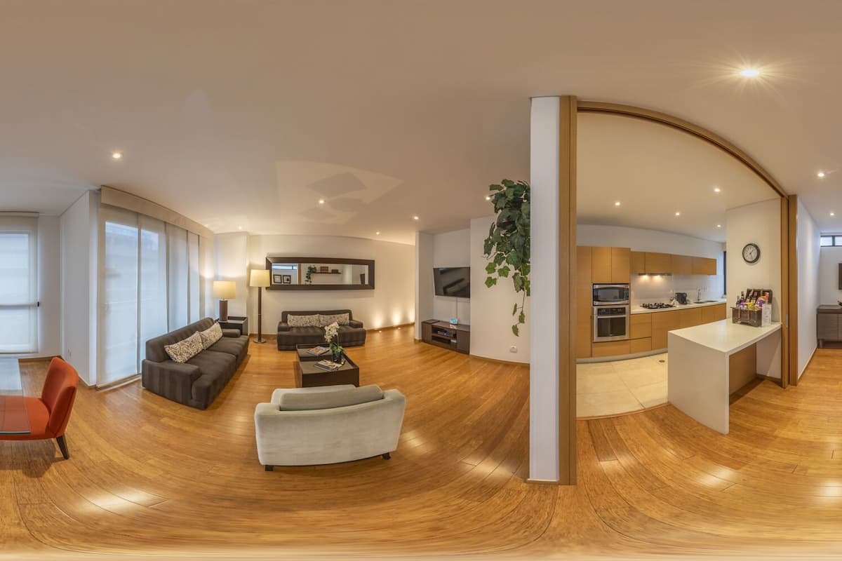 Ein großzügiger Wohnbereich mit einem Glastisch, Sofas und einer modernen Küchenzeile.