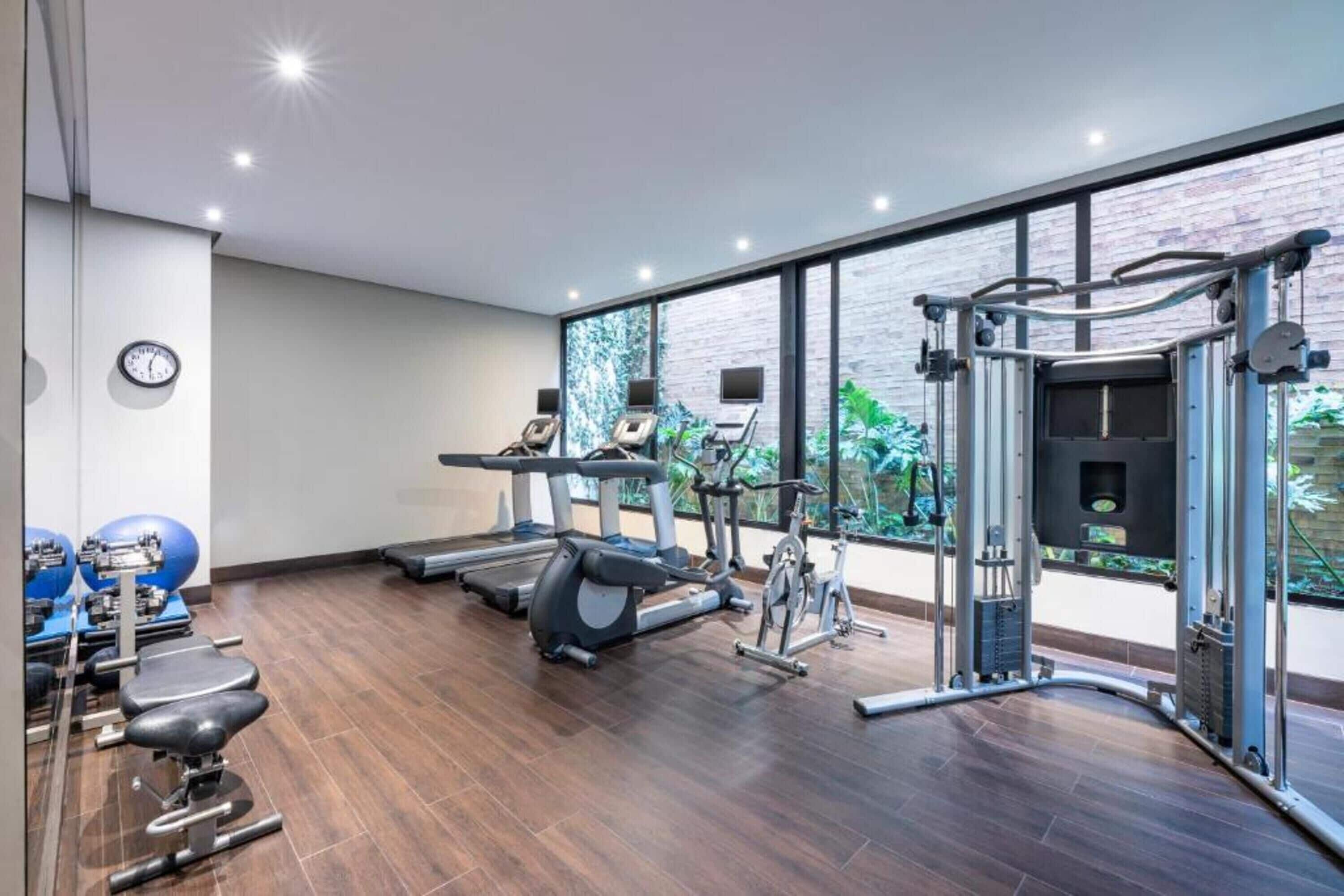 Et moderne fitnesscenter med løbebånd, crosstrainere og styrkeløftningsudstyr.