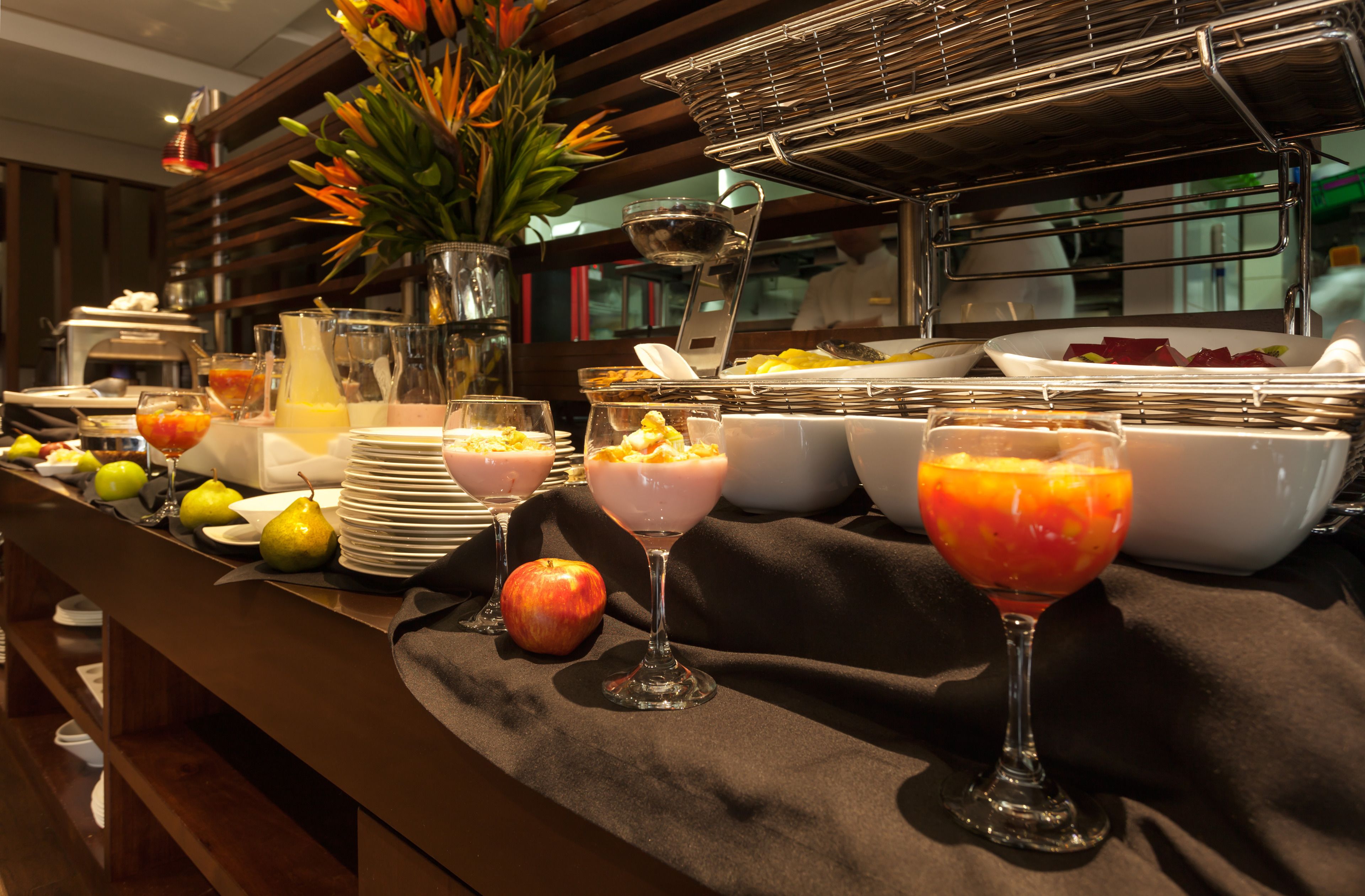 A buffet with various fruits, bowls of food, and a pitcher of orange juice.