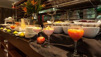 A buffet with various fruits, bowls of food, and a pitcher of orange juice.