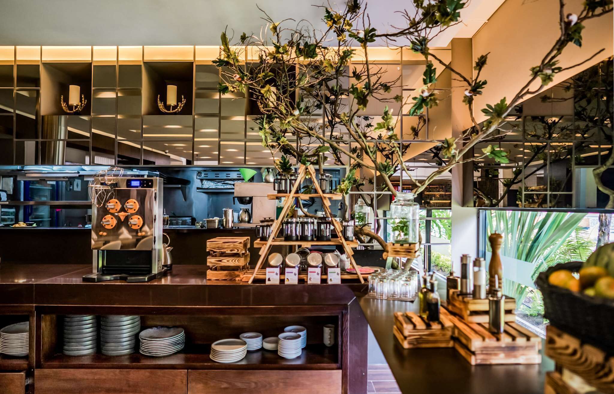 A modern kitchen with a central island, wooden shelves, and a decorative plant arrangement.