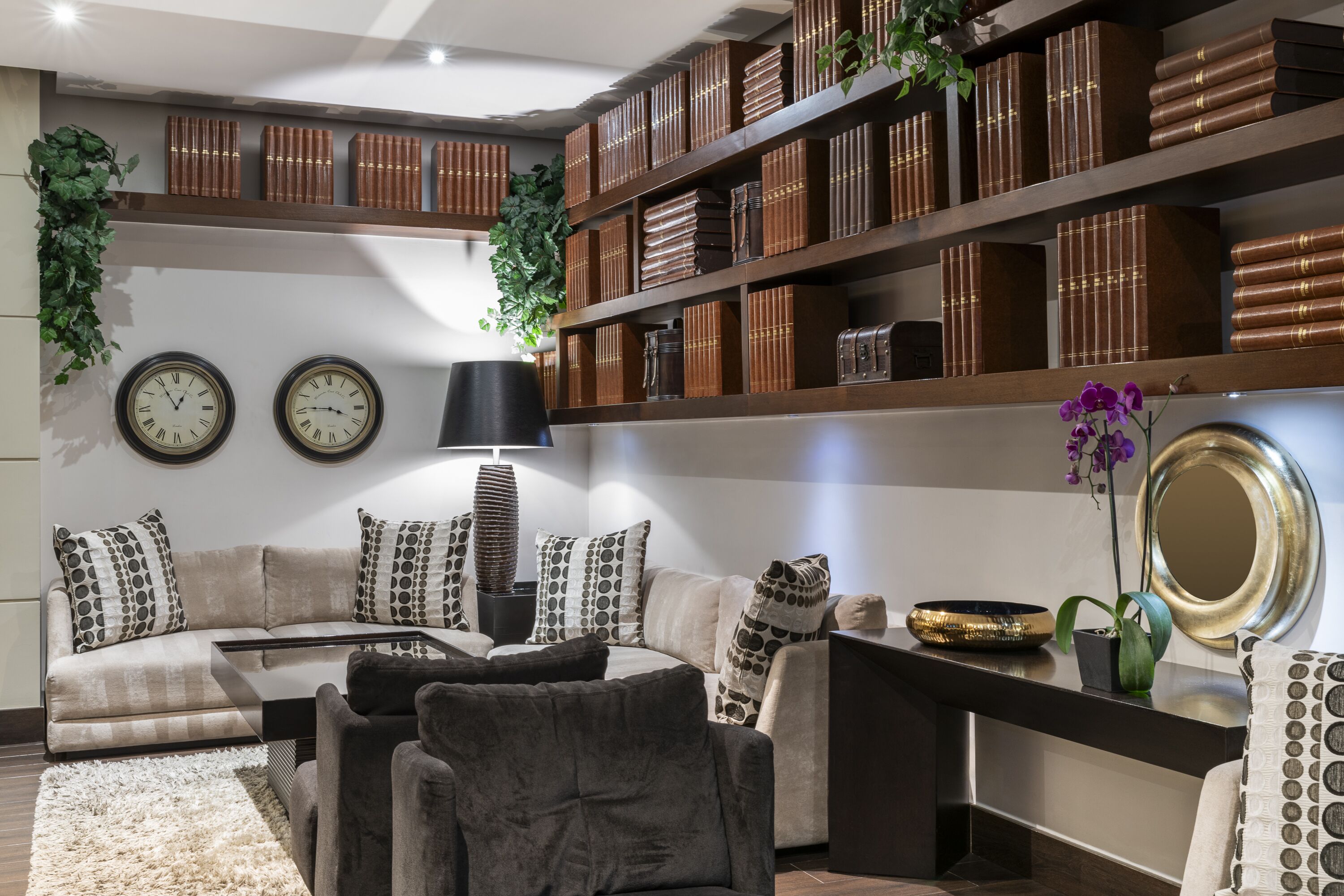 A modern living room with a sofa, armchairs, a coffee table, and a bookshelf filled with books.