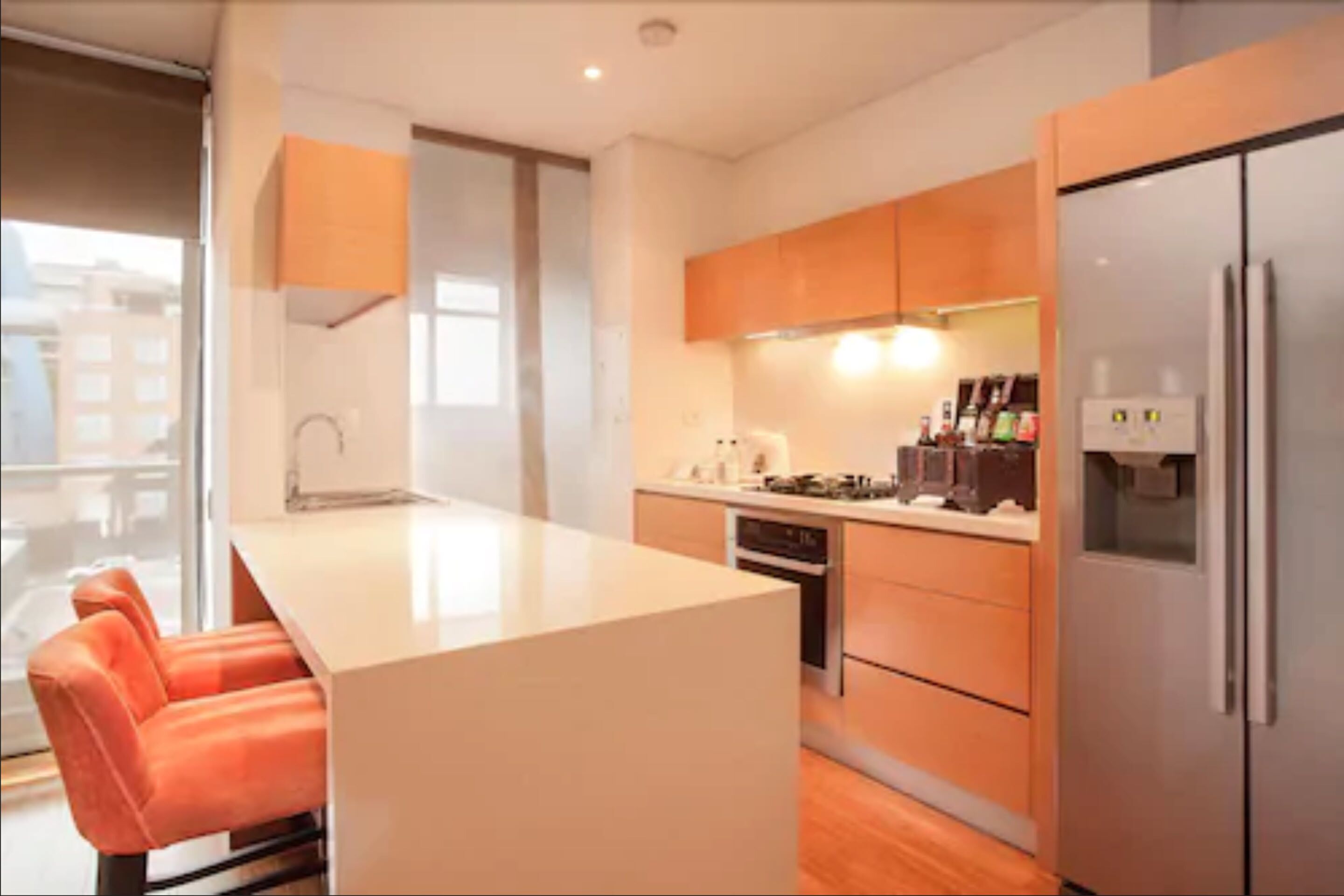 A modern kitchen with wooden cabinets, a central island, and a built-in oven.