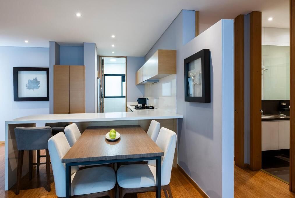Une cuisine moderne avec des meubles blancs, une table à manger en bois et un petit îlot central.