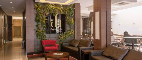 Un moderno vestíbulo de hotel con mostrador de recepción, zona de estar y comedor.