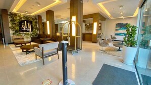 A modern hotel lobby with a reception desk, seating areas, and a large plant. - Açores Premium (Porto Alegre)