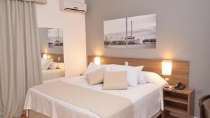 A hotel room with a large bed, bedside lamps, a nightstand with a phone, and two wall-mounted pictures. - Açores Premium (Porto Alegre)