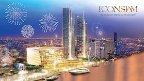 A cityscape with high-rise buildings, a waterfront, and fireworks in the sky. - Sala Rattanakosin Bangkok (Bangkok)