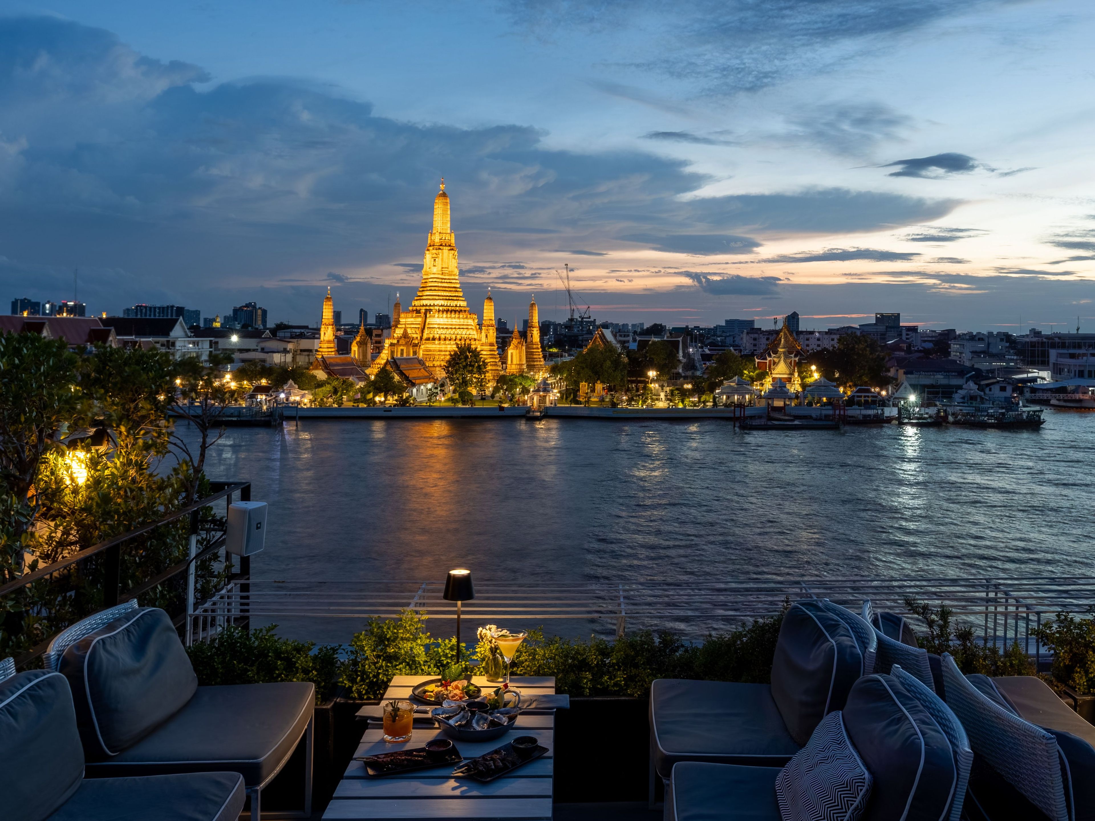 A waterfront view with a prominent golden pagoda and a dining area with outdoor seating.