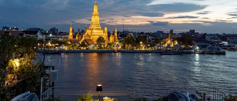A waterfront view with a prominent golden pagoda and a dining area with outdoor seating.
