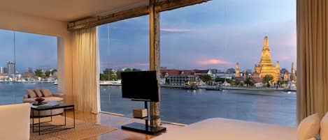 Habitación de hotel moderna con una cama grande, televisión y vistas a la ciudad y al río.