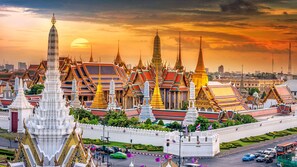 A temple complex with ornate structures and a sunset in the background. - Sala Rattanakosin Bangkok (Bangkok)