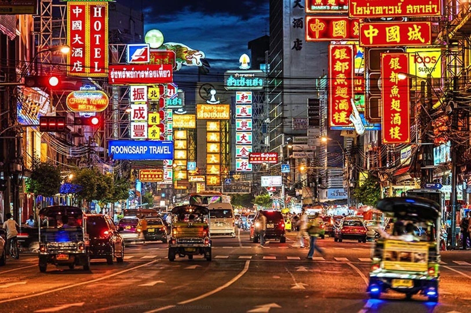 A busy street with neon signs and a hotel sign.