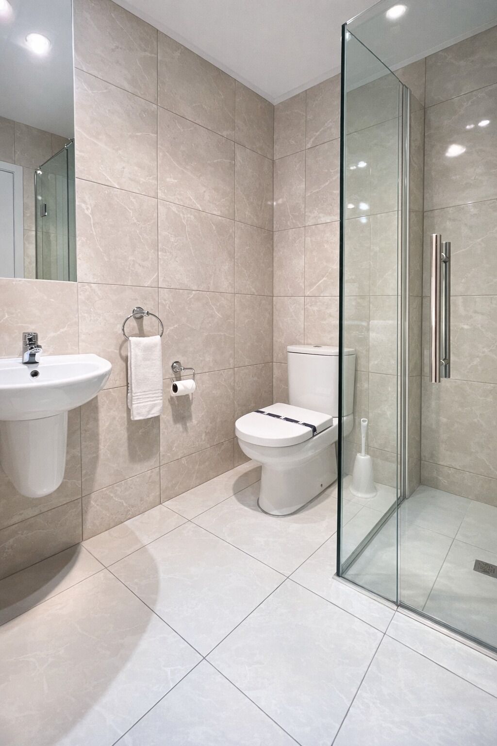 A modern bathroom with a glass shower enclosure, a sink, and a toilet.