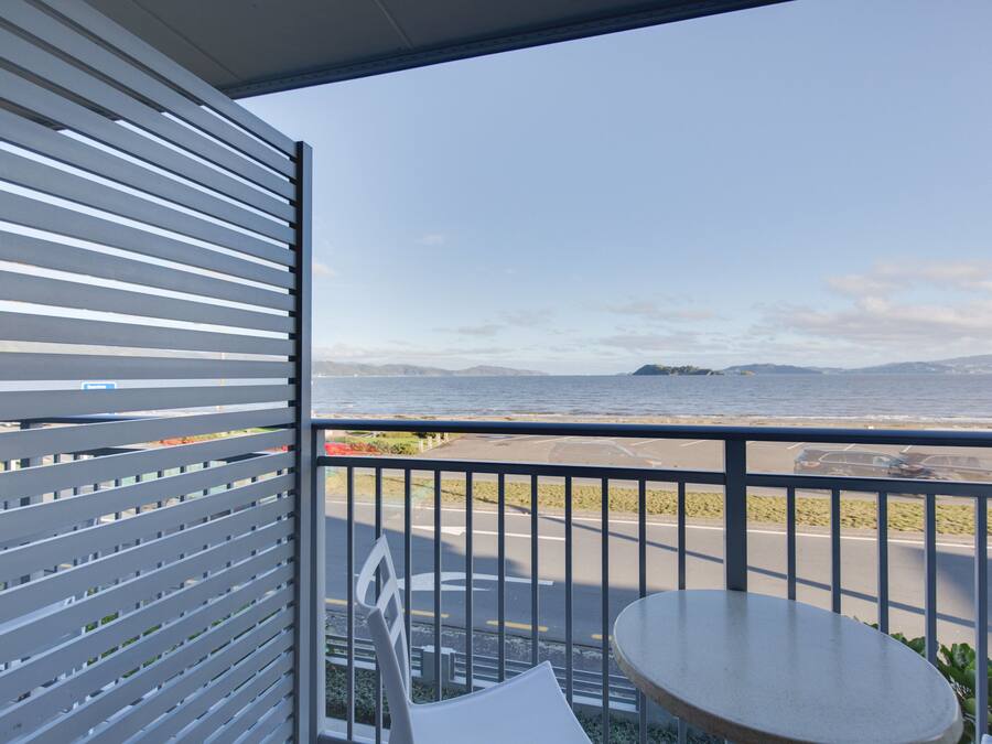 Un balcón con vistas al mar, una mesa y una silla.